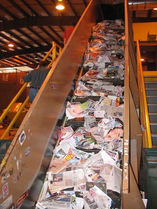Conveyor elevating newspaper for recycling