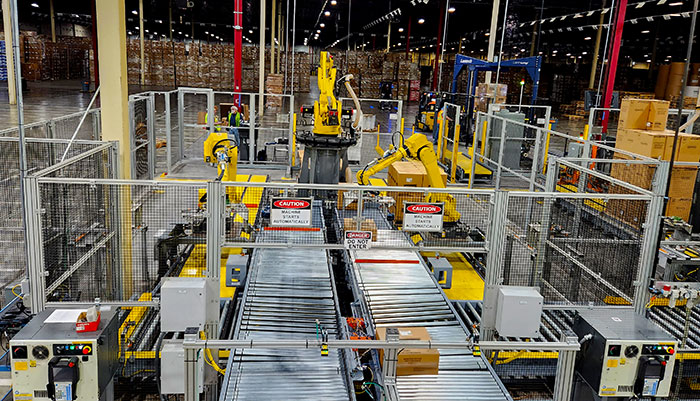 Conveyor system delivers and takes away loads to robotic palletizing cell