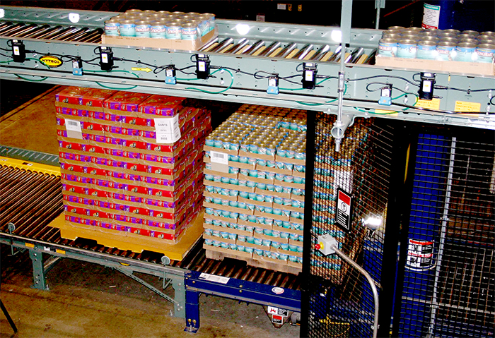 heavy pallet load of cans moving on a powered conveyor line