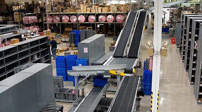 Belt conveyor with inclines to move products to overhead transport from picking area.
