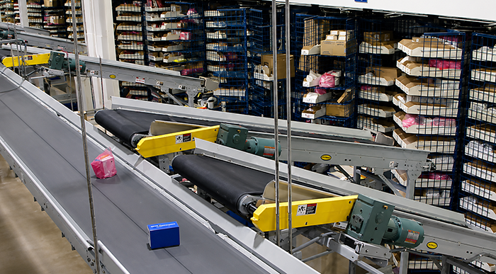 Belt conveyor line at TTI runs through carousel picking system, with inclines delivering product from picking to transportation.