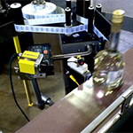 Conveyor labeling and barcode reader system for liquor distribution