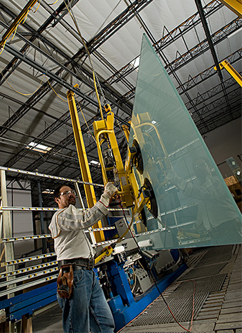 worker using crane and hoist system to lift heavy glass